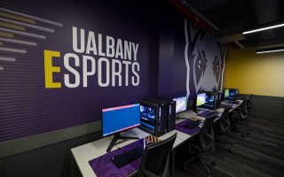 Lenovo Legion T7 gaming PCs in front of a UAlbany Esports graphic.
