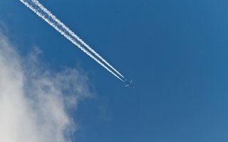 Contrails form across the sky behind a jet aircraft engine.