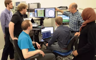 Students of Professor Nathaniel Cady, second from right, gather around a monitor of a semiconductor wafer in a lab at Albany Nanotech.
