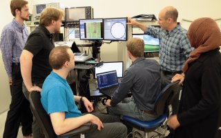 Students of Professor Nathaniel Cady, second from right, gather around a monitor of a semiconductor wafer in a lab at Albany Nanotech.
