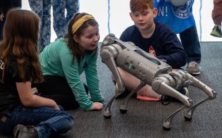 Young students watch a robotic dog in action at STEM and Nanotechnology Family Day at ETEC in February, 2024.