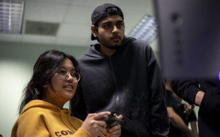 Students look at a computer screen with preparing game design projects for Showcase.