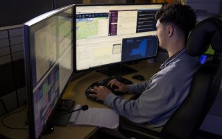 A student looks at dual monitors from inside the Emergency and Risk Communication Message Testing lab at ETEC.