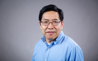 Headshot of Aiguo Dai wearing a blue button-down shirt.