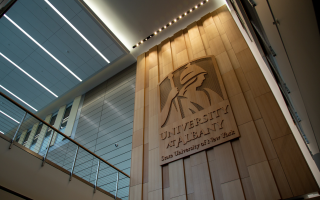 A wooden image of Minerva with the words "University at Albany State University of New York" is seen on a wall in the ETEC lobby