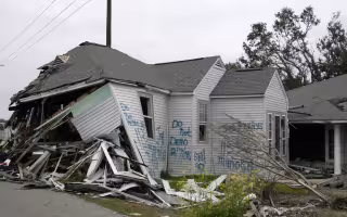 A damaged home with "do not demo" signage on it following Hurricane Katrina.