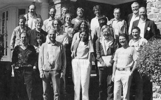 Black and white group photo featuring 21 men and women standing on steps in front of a stone building.