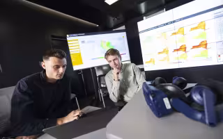Two researchers review weather data on a laptop from inside the XCITE Lab at UAlbany.