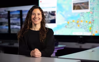 Carly Sutter sits in front of a map of New York inside UAlbany’s xCITE lab.