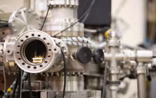 a closeup of metal tubes and wires that are part of an ion beam accelerator.