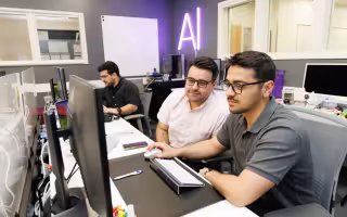Abdullah Canbaz and Mikail Demir stare at a computer screen inside the AI in Complex Systems Lab.