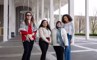 Four smiling students stand together on the Academic Podium