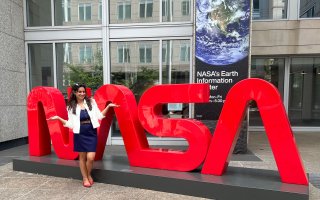 Vasuda Trehan stands in front of a large red NASA logo.