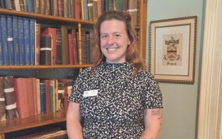 Tompkins stands in front of bookshelf at Seward House Museum