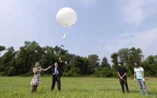 Michelle Campbell and Sen. Jim Tedisco launch a weather balloon into the sky from a field at Hudson Crossing Park.