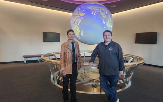 CEHC's Ariel Pinto and Center for Internet Security's Sean Atkinson stand in front of the Science on a Sphere globe at ETEC.