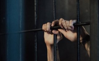 hands grasp prison bars