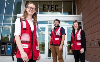 Nancy Kreis, Mike Clahane and Erin Golden stand in front of the ETEC building in American Red Cross vests.