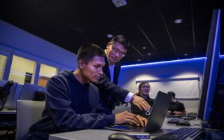 Alan Wang works with a student on his class project from the Cyber Range lab.