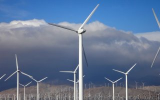 A field of wind turbines with dark clouds above them.
