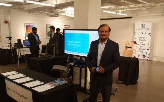 Kesh Kesavadas stands in front of table and presentation screen at the MATTER conference.