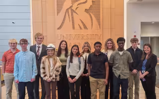 High school seniors from the New Visions program take a photo in front of the Minerva logo at ETEC.