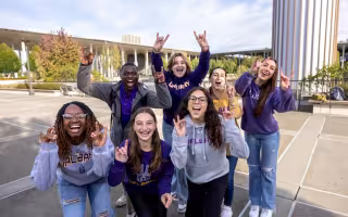 UAlbany students enthusiastically sharing their Great Dane hand signal on the podium