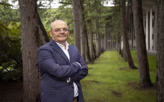 Andrei Lapenas stands with trees in the Academic Podium courtyard.