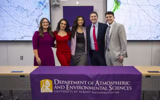 UAlbany roundtable panelists take a photo together in front of a Department of Atmospheric and Environmental Sciences table covering.