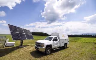 A New York State Mesonet truck parks in front of solar panels powering the network's Lake Placid site.