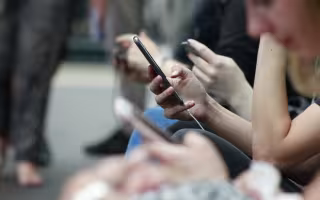 People seated next to each other scroll on their phones