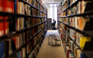 A tunnel of bookshelves lead to a student studying ahead of finals week.