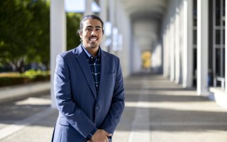Parmesh Thakoordial stands between the columns on the Academic Podium.