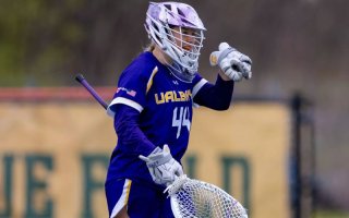a women's lacrosse player in a purple UAlbany uniform