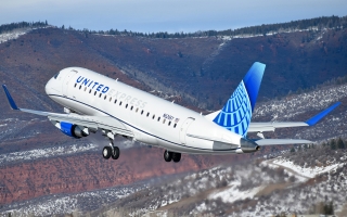 A jet labeled "United Express" flies over mountains.