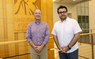 Andy Berglund and Abdullah Canbaz stand in front of a Minerva wood panel at ETEC.