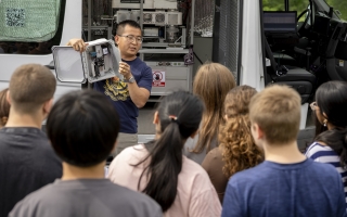 ASRC's Jie Zhang holds up instrumentation used in the mobile lab in front of Lisha Kill middle school.
