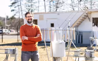 Justin Minder stands in front of Mesonet instrumentation at the ETEC yard.