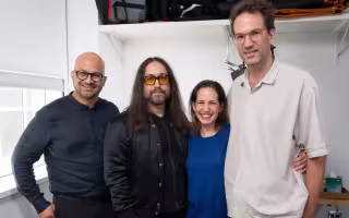 Four people, including three men and a woman, pose for a picture together inside a room