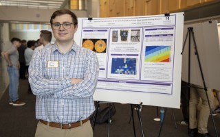 A young male student poses with a research poster at ETEC