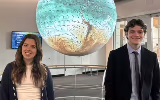 UAlbany students Micaela Maywald and Michael Miller stand in front of the Science-on-a-Sphere globe at ETEC.