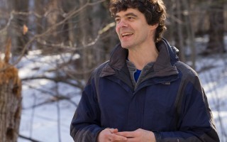 Mathias Vuille stands in a wooded area on campus during the winter season.
