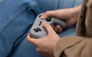 A student plays with a retro controller inside the Game Hub.