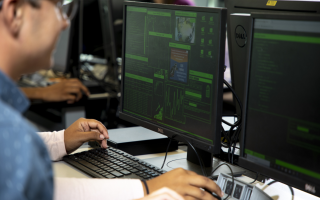 A student sits at a computer with graphs and charts on the screen