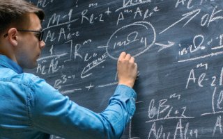 UAlbany student writing mathe problems on a chalk board