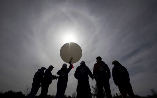 UAlbany students prepare to launch a weather balloon in near darkness at Fort Drum.
