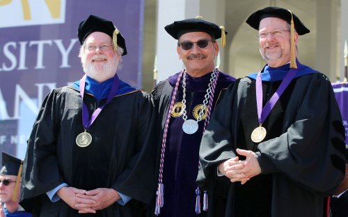 Three men in University regalia, wearing medalions, stand together, smiling