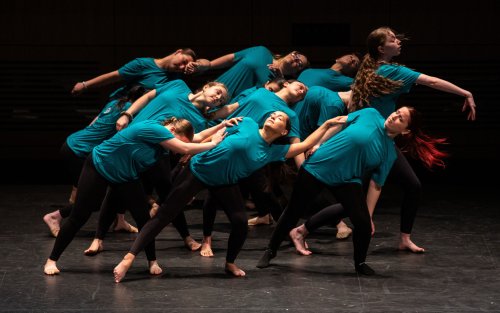 Students in blue shirts and black leggins perform artistic dance on stage at UAlbany Showcase Day 2024.