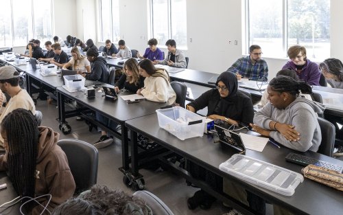 students work on projects at communal tables in class.