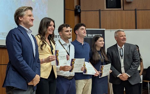 Natalie Hinrichsen standing with her poster award certificate along with other students on RNA Day.